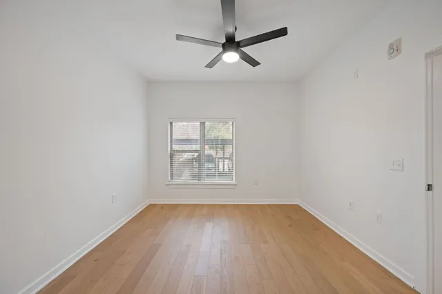 an empty room with wooden floor and windows