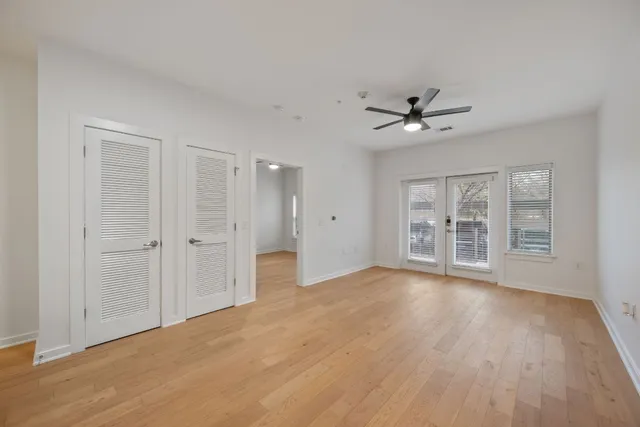 a view of an empty room with a window and a kitchen