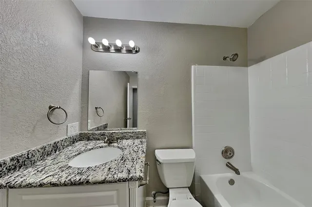 a bathroom with a granite countertop sink a toilet and a mirror