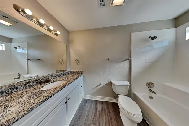 a large spacious bathroom with a granite countertop toilet a sink and a bathtub