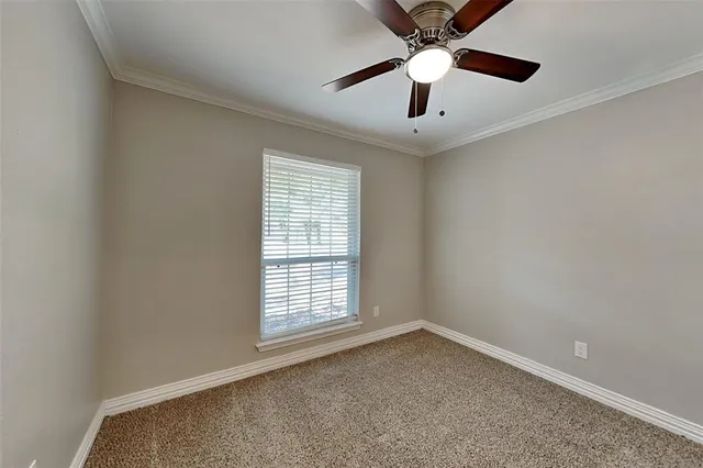 an empty room with ceiling fan and windows
