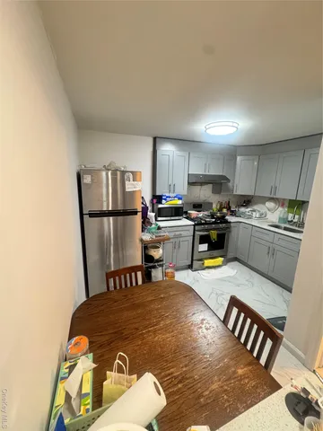 a kitchen with a refrigerator a stove a sink and a dining table with wooden floor