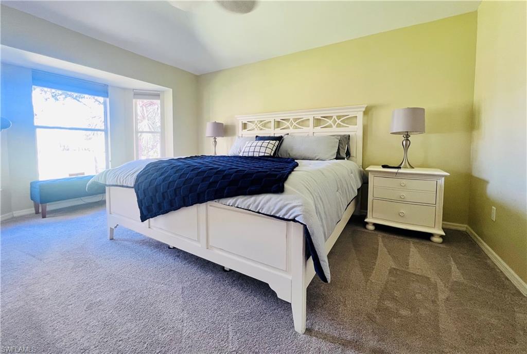8073 Panther Trail, Unit 1404 Naples, FL 34113 - Photo 13 of 29 a bedroom with a bed lamp and a window