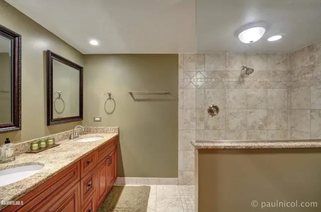 a bathroom with a granite countertop sink a mirror and shower