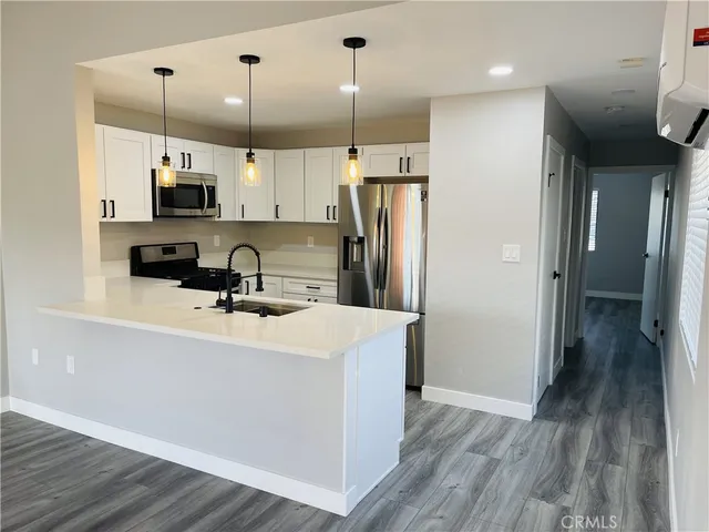 a kitchen with a refrigerator a sink and a wooden floor