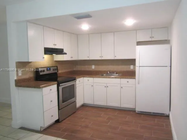 a kitchen with granite countertop white cabinets and white appliances