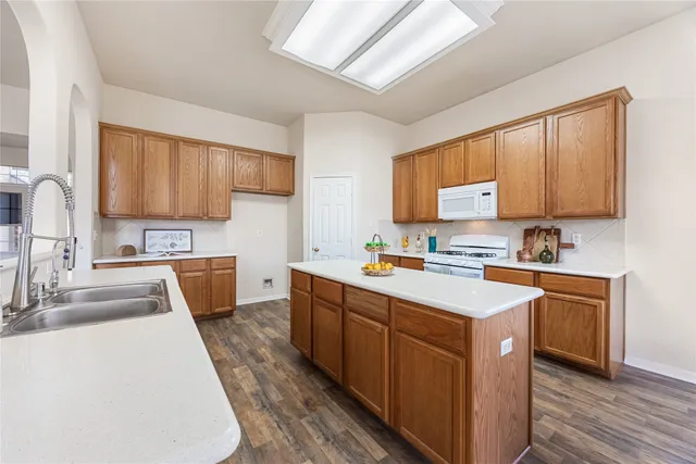 a kitchen with stainless steel appliances granite countertop a sink a stove and a wooden floors