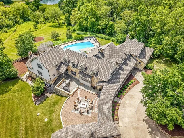 an aerial view of a swimming pool with a yard and large trees
