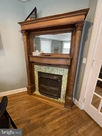 a view of an empty room with wooden floor and a fireplace