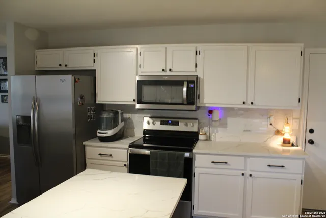 a kitchen with white cabinets and stainless steel appliances
