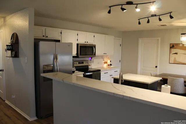 a kitchen with refrigerator a microwave a sink and cabinets