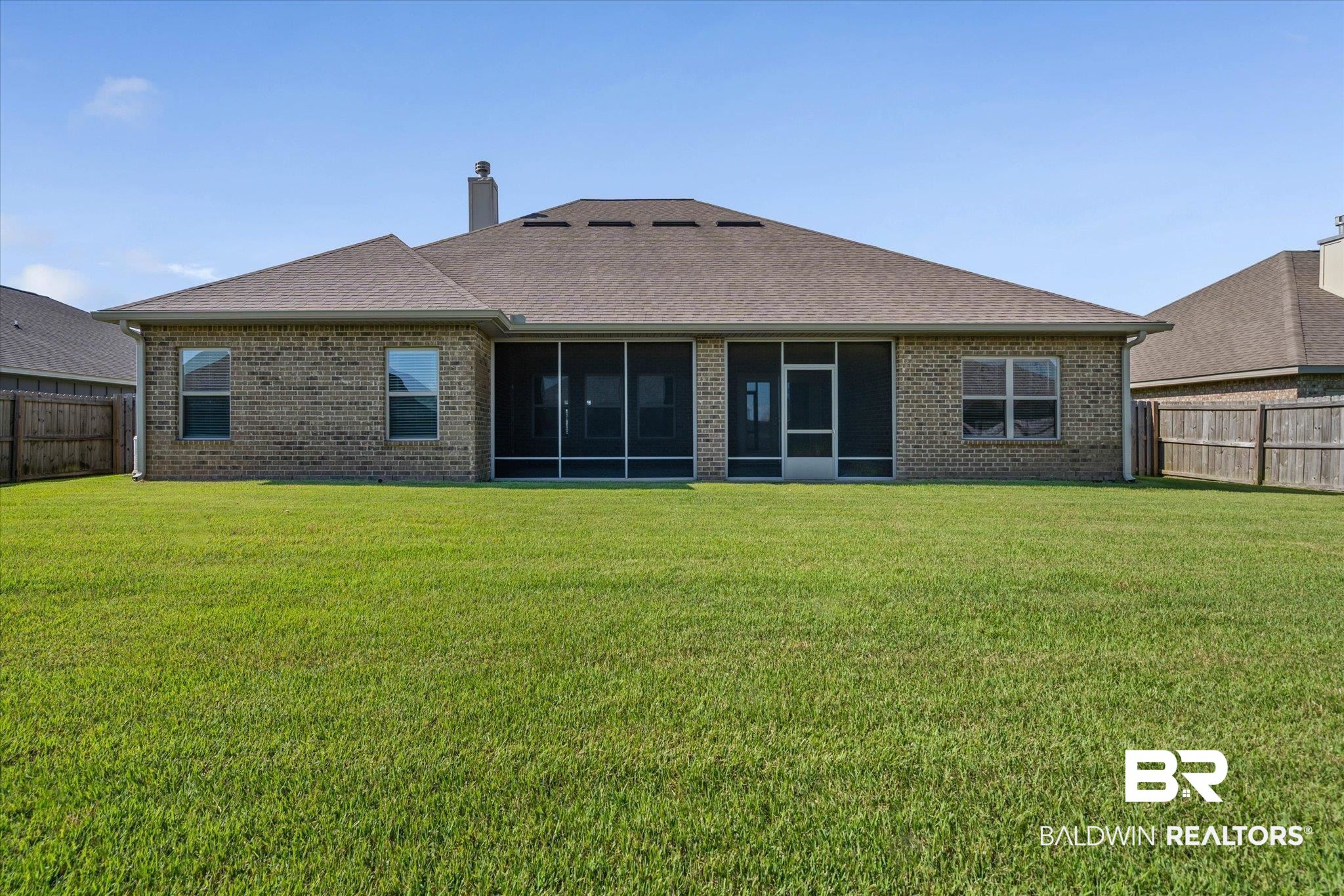 10207 Dunleith Loop Daphne, AL 36526 - Photo 18 of 23 Back of house featuring a fenced backyard, a chimney, a shingled roof, a sunroom, and brick siding