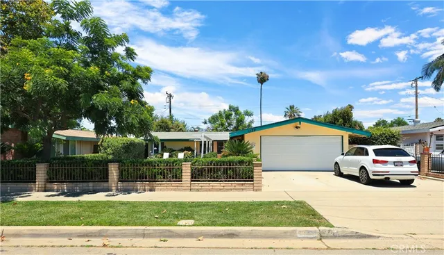 a front view of a house with a garden and tree