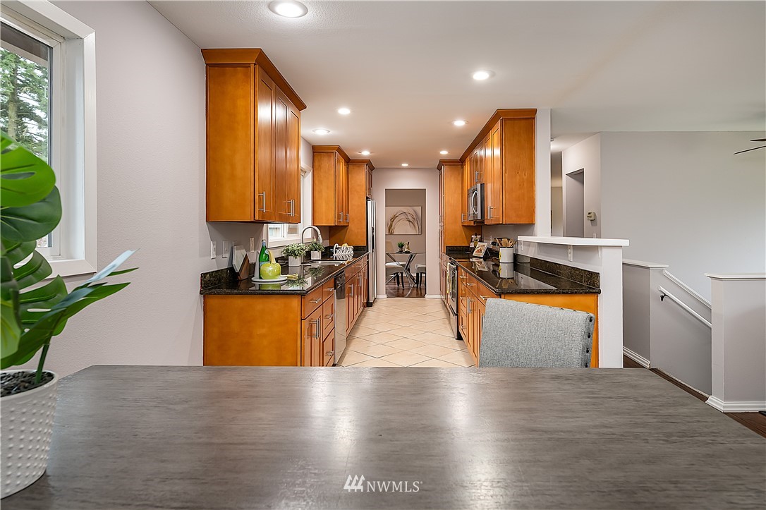 21723 2nd Avenue Southeast Bothell, WA 98021 - Photo 5 of 27 a kitchen with stainless steel appliances granite countertop wooden floors a stove a sink and a refrigerator
