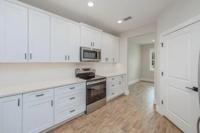 a kitchen with white cabinets stainless steel appliances and a sink