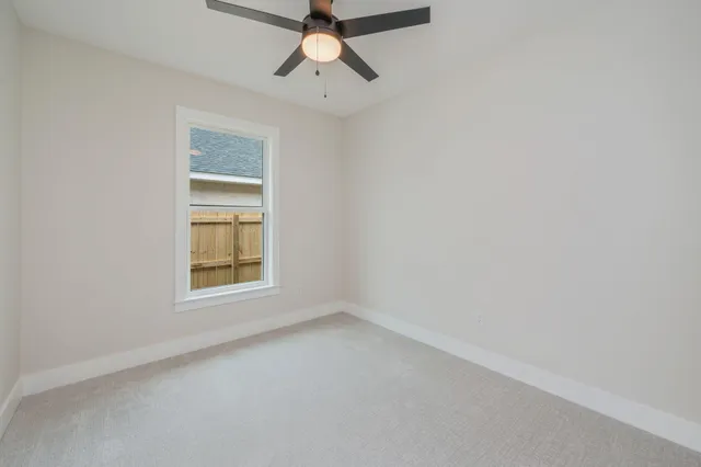 an empty room with a window and ceiling fan