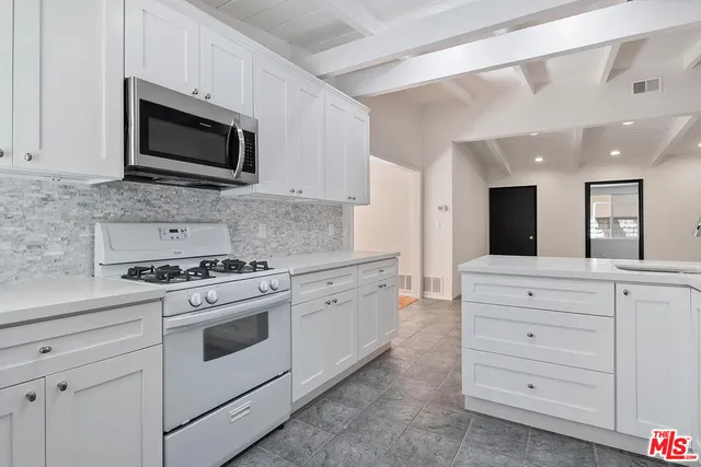 a view of an empty room with wooden floor and windows