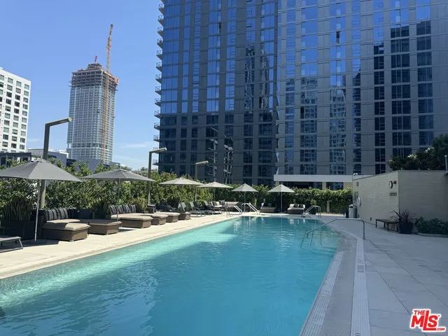 a view of a roof deck with couches under an umbrella with a fire pit