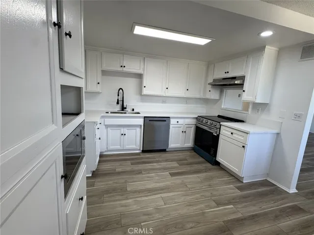a kitchen with white cabinets appliances and sink