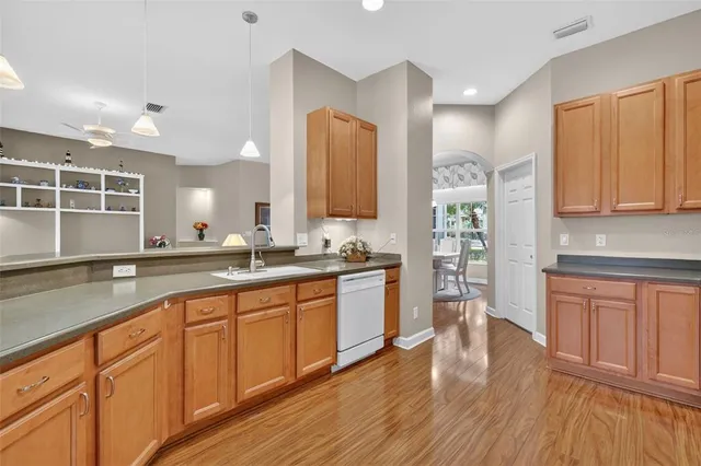 a kitchen with stainless steel appliances granite countertop a refrigerator a stove top oven a sink and dishwasher with wooden floor