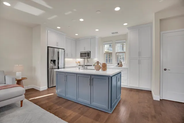 a living room with stainless steel appliances kitchen island granite countertop a refrigerator and a sink