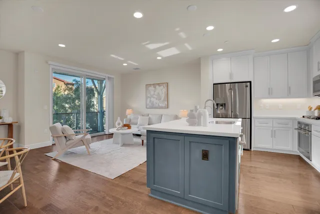 a living room with stainless steel appliances granite countertop furniture sink and wooden floor