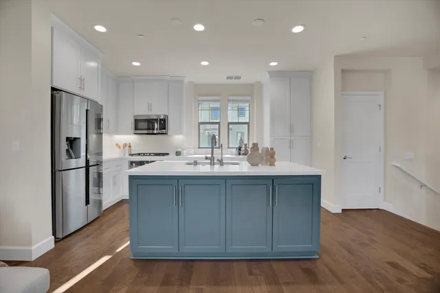 a kitchen with kitchen island a sink stainless steel appliances and cabinets