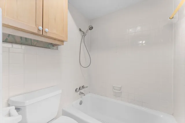 a bathroom with a bath tub with a toilet next to window