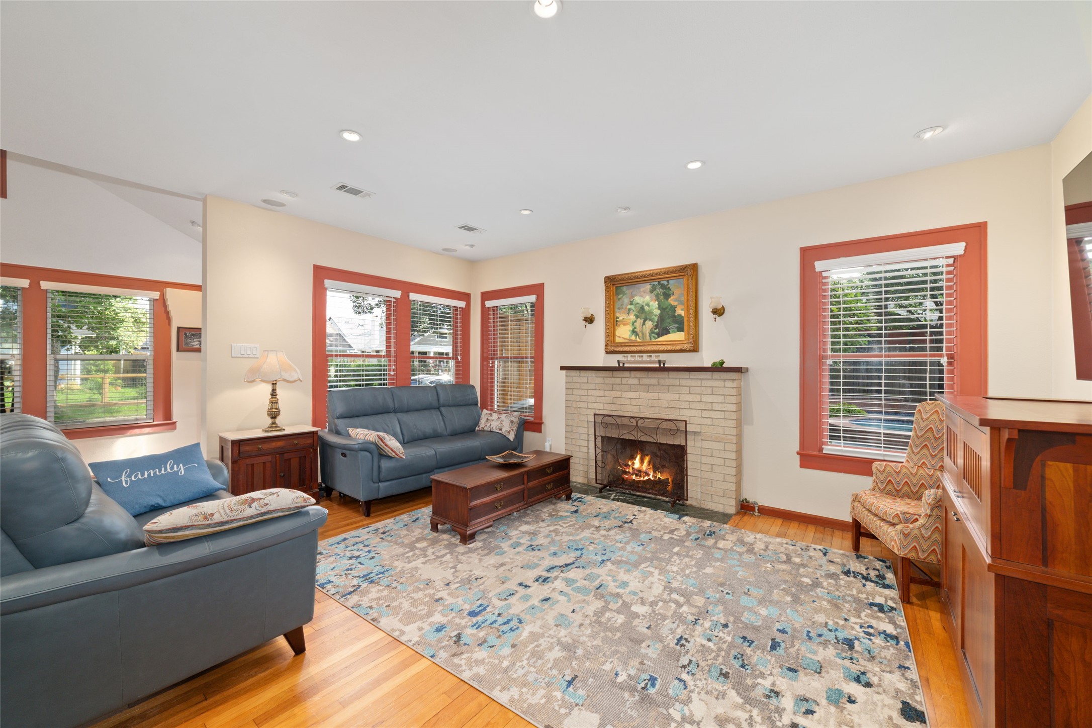 1613 California Street Houston, TX 77006 - Photo 11 of 50 Anchored by a gas fireplace and framed by oversized windows, the living room balances timeless architecture with everyday comfort. Natural light dances across original hardwood floors, creating a space that feels gracious without ever feeling formal.