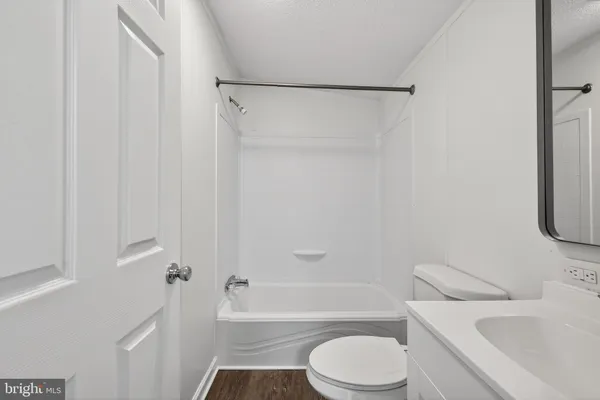 a view of a hallway with wooden floor and a bathroom