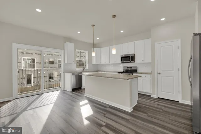 a kitchen with stainless steel appliances granite countertop a refrigerator a sink dishwasher a oven and white cabinets with wooden floor