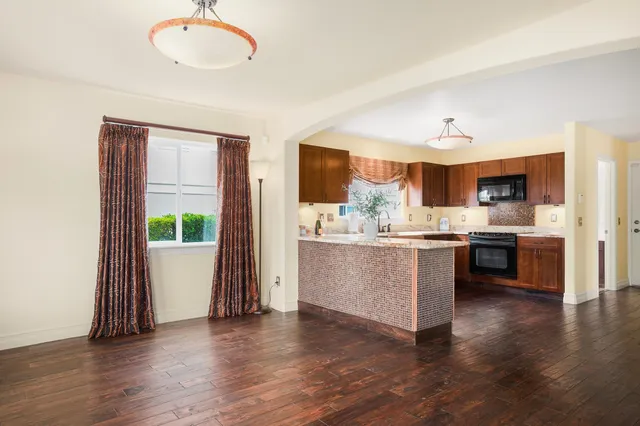 a kitchen with kitchen island granite countertop a sink cabinets and wooden floor