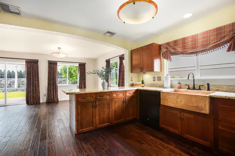 a large kitchen with stainless steel appliances granite countertop a stove a sink dishwasher and a microwave oven with wooden floor