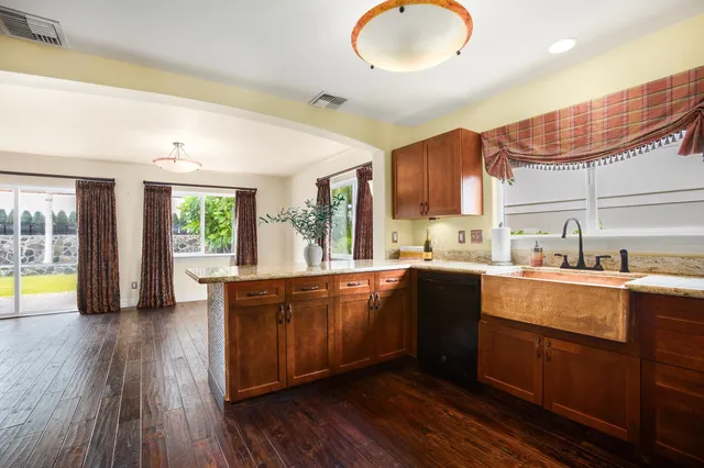 a large kitchen with stainless steel appliances granite countertop a stove a sink dishwasher and a microwave oven with wooden floor