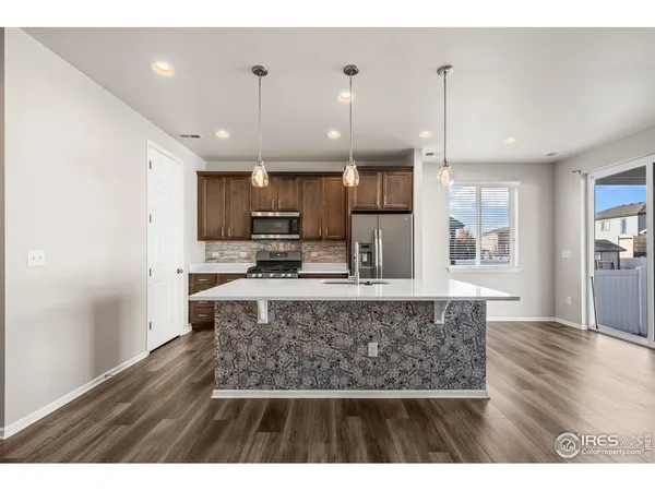 a large kitchen with stainless steel appliances kitchen island a large island a stove a refrigerator white cabinets and wooden floor
