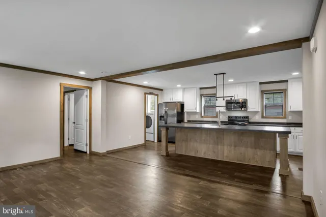 a kitchen with stainless steel appliances granite countertop a refrigerator a stove a sink dishwasher and white cabinets with wooden floor