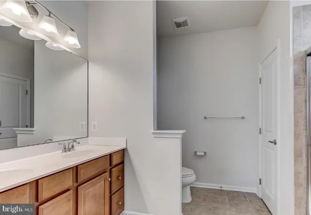 a bathroom with a sink a toilet a light fixture and a mirror