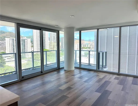 a view of an empty room with wooden floor and a window