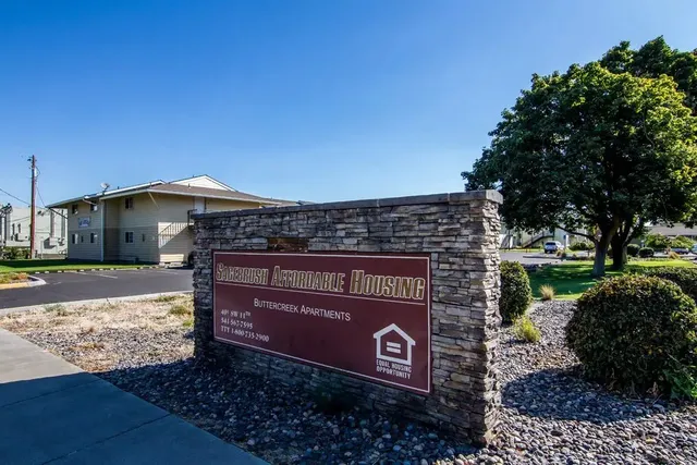 a sign board with a house in the background