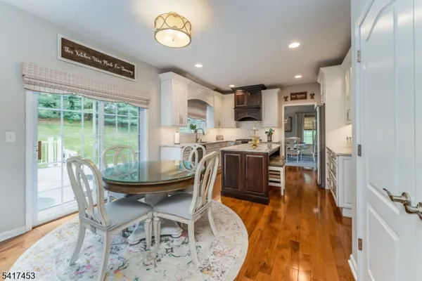 a dining room with stainless steel appliances granite countertop a stove a refrigerator a oven a dining table and chairs with wooden floor