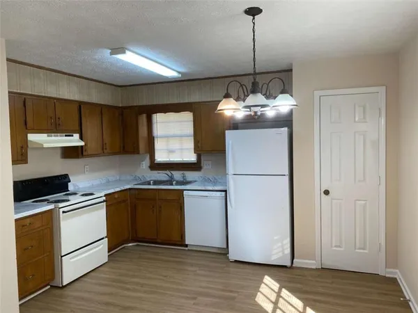 a kitchen with kitchen island granite countertop wooden cabinets and white appliances