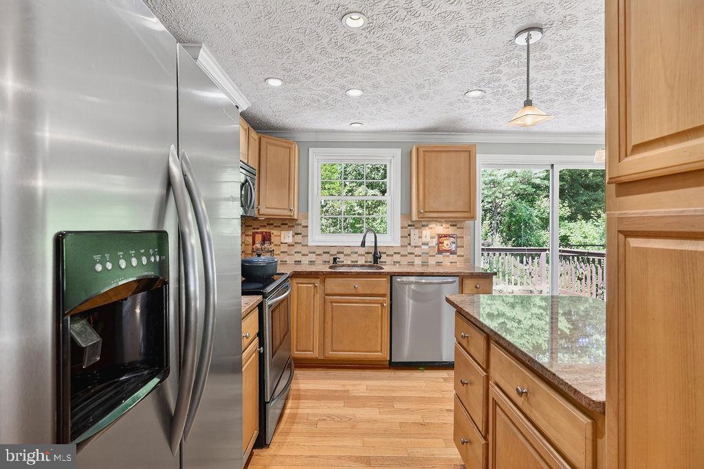 8471 Great Lake Lane Springfield, VA 22153 - Photo 13 of 65 a kitchen with kitchen island granite countertop a refrigerator a sink dishwasher a stove and a dining table with wooden floor