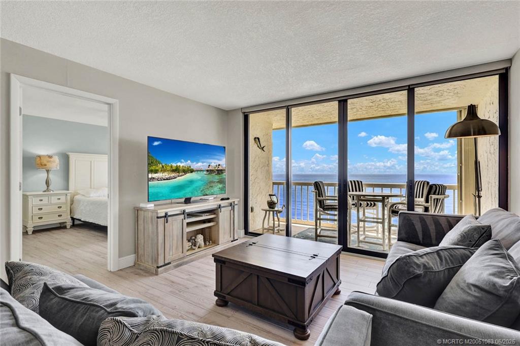 10600 South Ocean Drive, Unit 802 Jensen Beach, FL 34957 - Photo 16 of 39 a living room with furniture a large window and a flat screen tv
