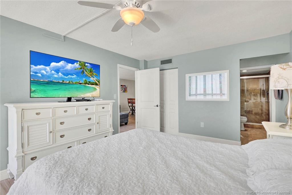 10600 South Ocean Drive, Unit 802 Jensen Beach, FL 34957 - Photo 22 of 39 a bedroom with a bed and a flat screen tv in white walls