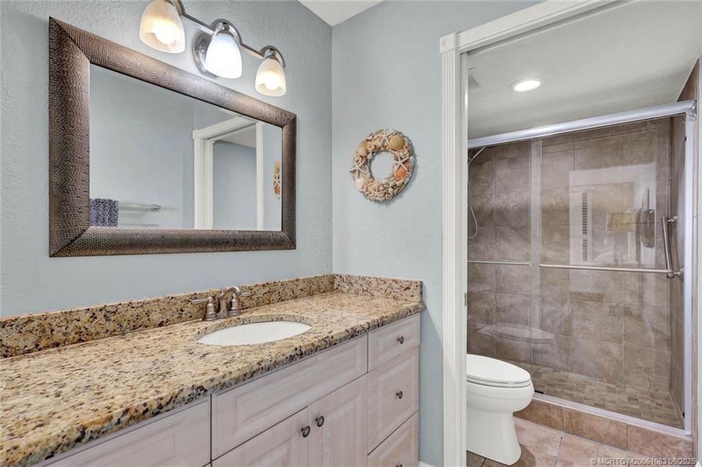 10600 South Ocean Drive, Unit 802 Jensen Beach, FL 34957 - Photo 23 of 39 a bathroom with a granite countertop sink a toilet and a mirror