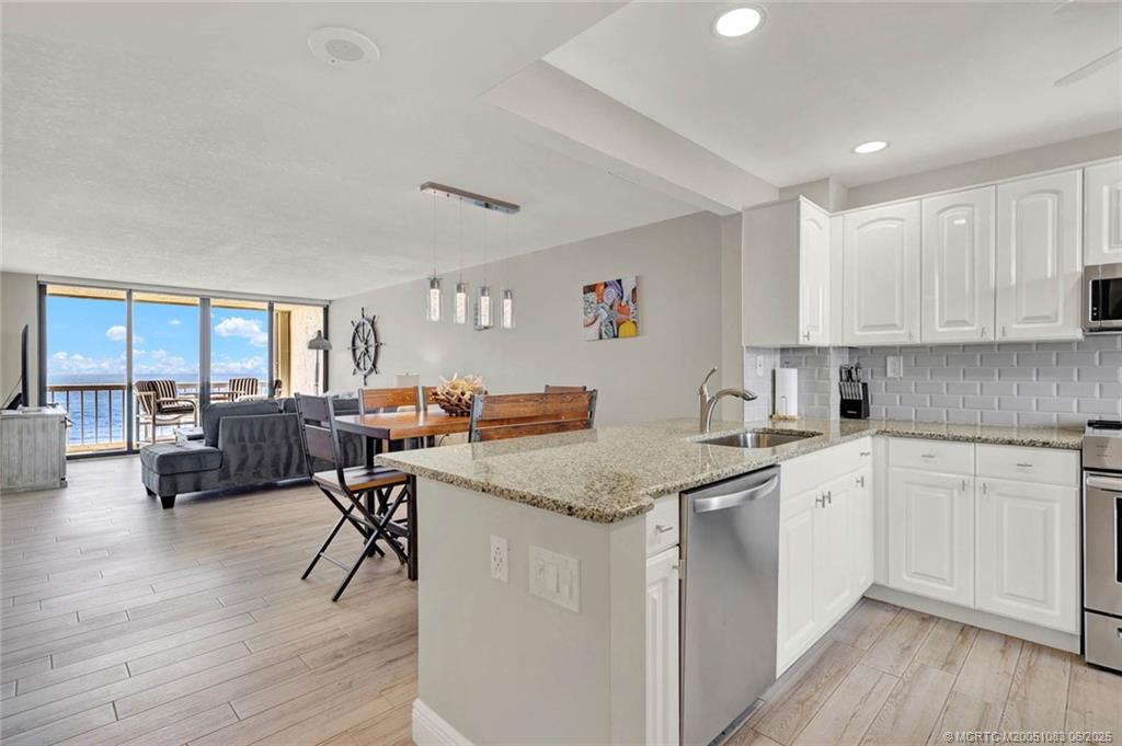 10600 South Ocean Drive, Unit 802 Jensen Beach, FL 34957 - Photo 7 of 39 a open kitchen with stainless steel appliances granite countertop a stove and white cabinets