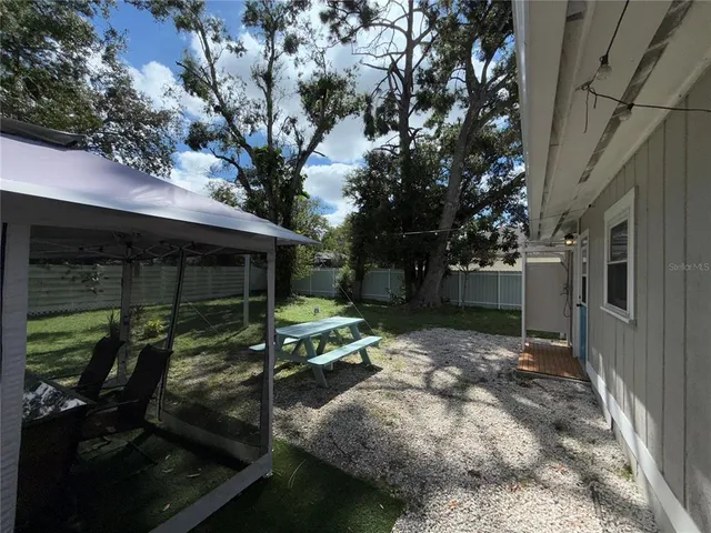 a view of backyard with table and chairs and a large tree