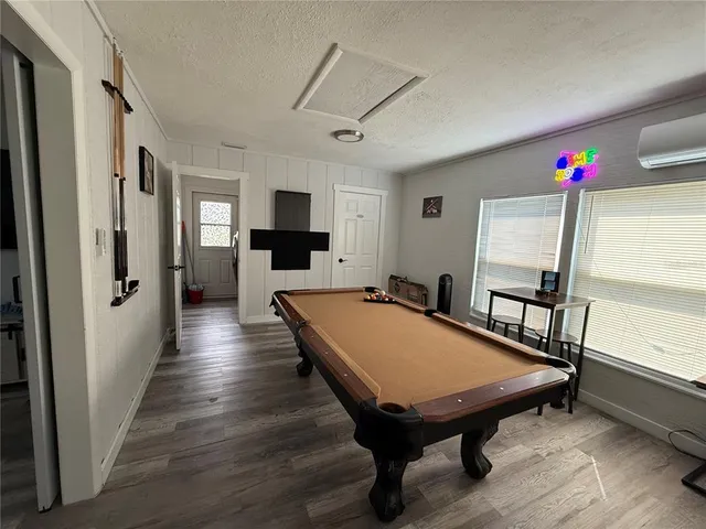 a living room with pool table and a wooden floor
