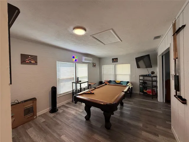 a room with furniture pool table wooden floor and windows