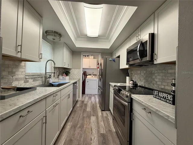 a kitchen with stainless steel appliances granite countertop a sink a stove top oven and cabinetry